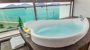 A large bathtub with a view of the sea through a window. - Geoje Rockspa Pension (Geoje)