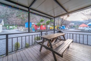 Un espacio al aire libre techado con mesas de picnic y vistas a edificios coloridos al fondo.