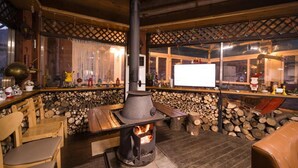 Una habitación acogedora con estufa de leña, muebles de madera y vistas por una ventana.