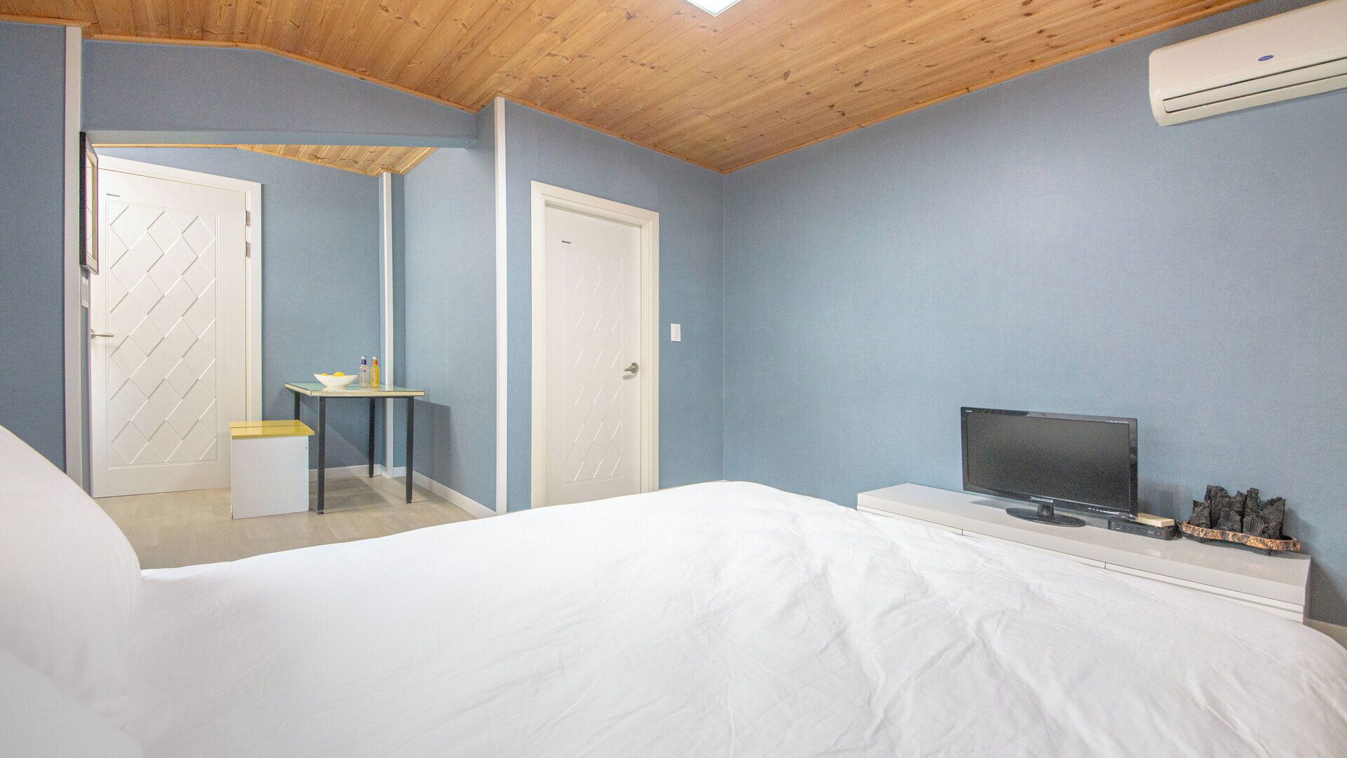 A bedroom with a bed, a television, and a desk with a chair.