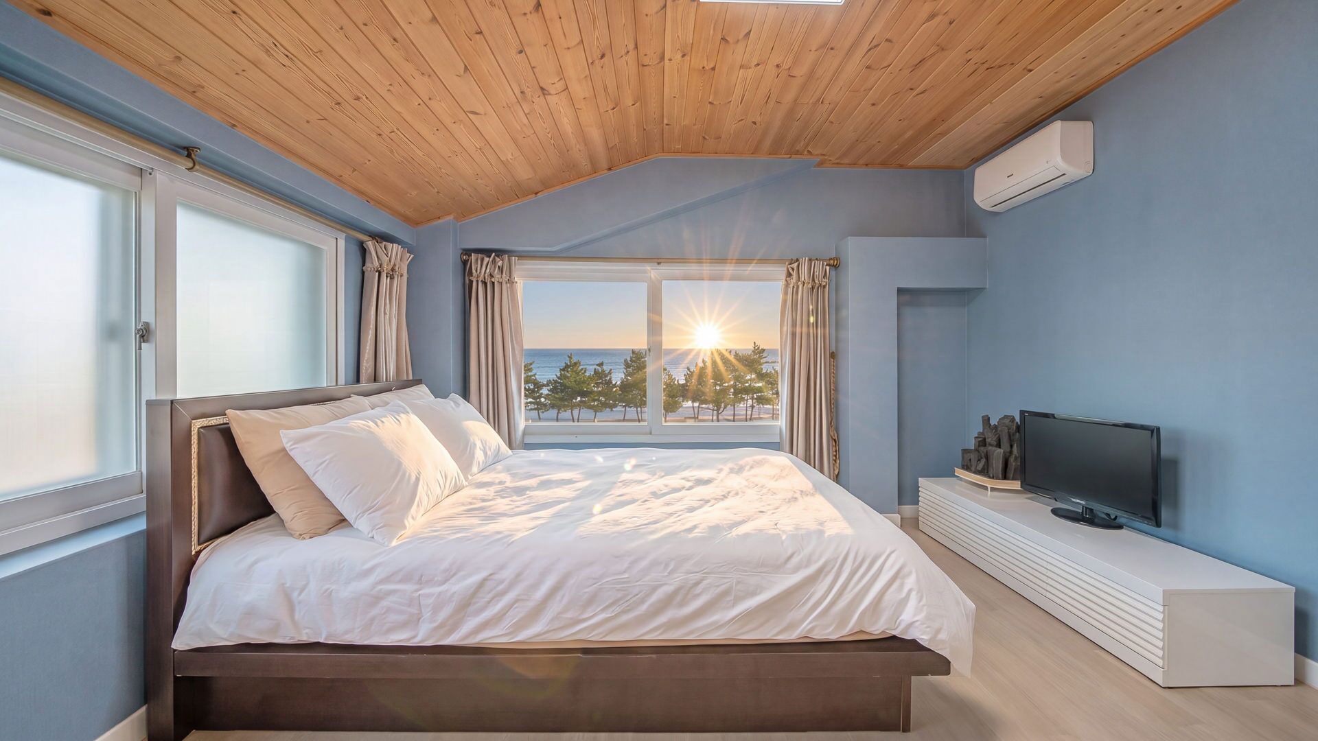 Un dormitorio con cama, televisor y vista al mar.