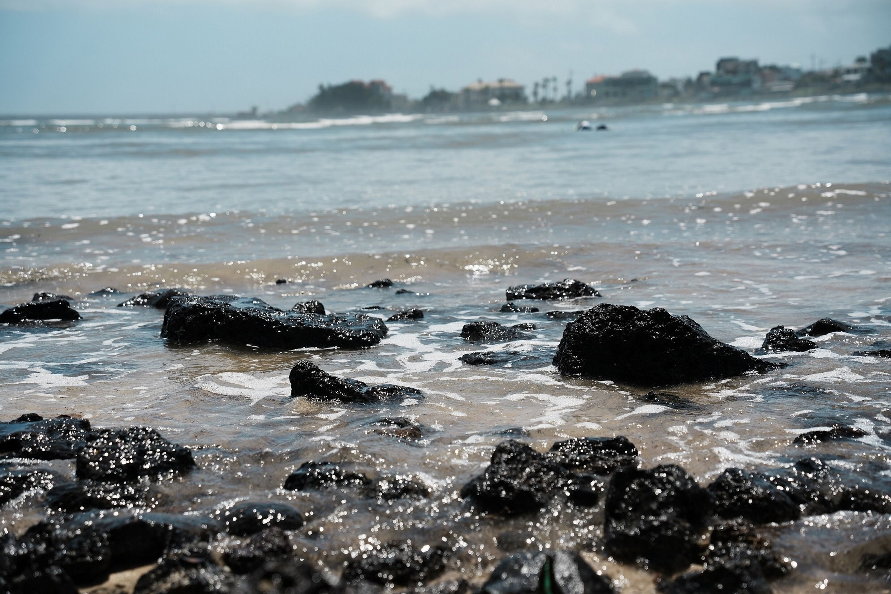 A rocky shoreline with waves gently lapping against the rocks.