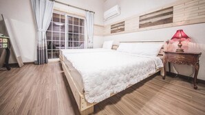 A bedroom with a wooden bed, a window with curtains, a bedside table with a lamp, and a wall-mounted air conditioner. - Jeju Ppalkanpungcha Pension (Jeju City)