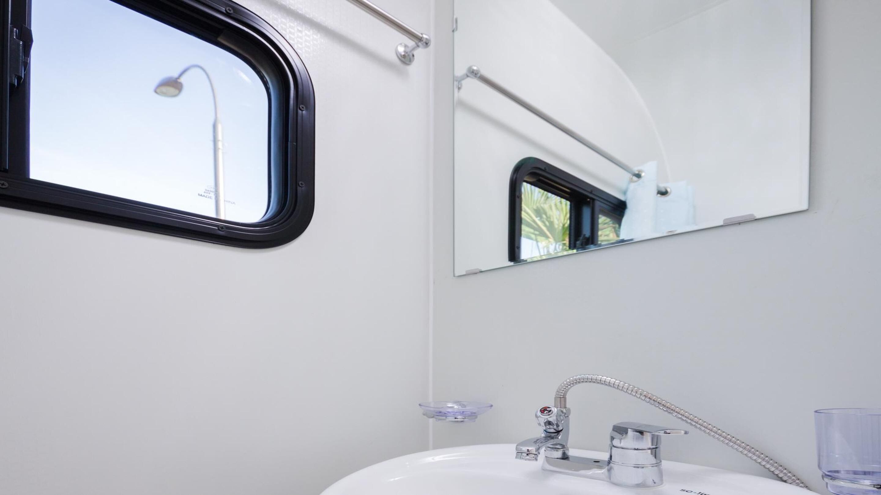 A bathroom with a white sink, a mirror, and a shower head.