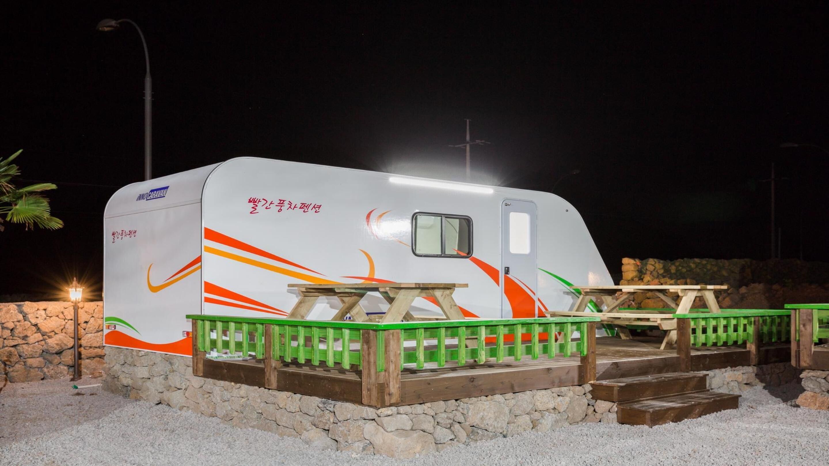 Un camping-car à l’arrêt, équipé d’une table de pique-nique et d’une petite terrasse.