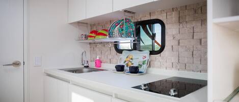 Cocina compacta con encimera blanca, un lavamanos y ventana con vistas.