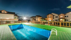 A swimming pool with a wooden deck and a wooden fence. - Jeju Ppalkanpungcha Pension (Jeju City)
