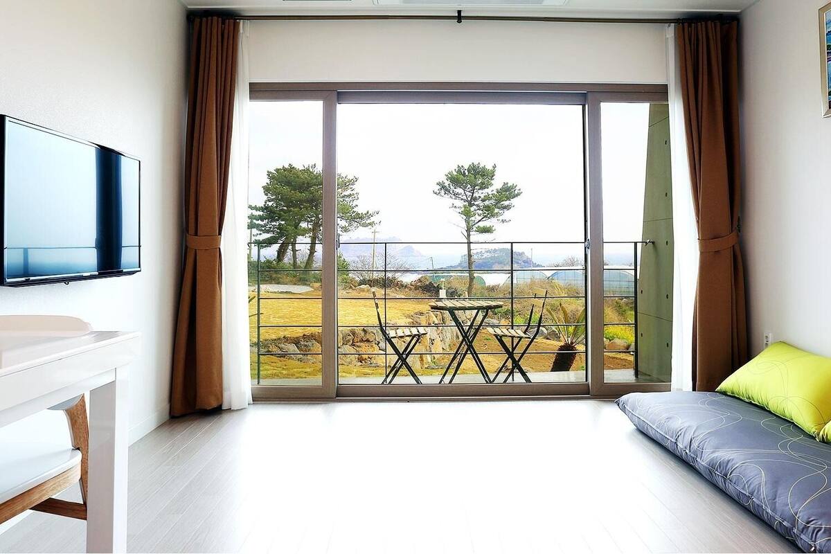 A modern room with a sofa, a TV, and a balcony with a table and chairs.