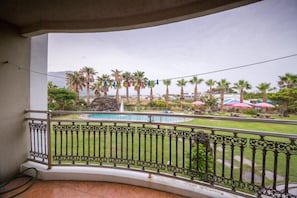 A balcony with a view of a swimming pool, palm trees, and outdoor seating areas. - Seogwipo Jejuhae-anhyuyang Pension (Seogwipo)