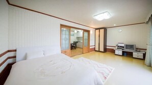 A bedroom with a large bed, a desk with a television, and a sliding door leading to a bathroom. - Seogwipo Jejuhae-anhyuyang Pension (Seogwipo)