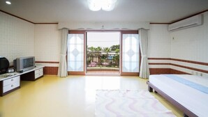 A bedroom with a bed, a TV on a stand, a small table, and a window with curtains. - Seogwipo Jejuhae-anhyuyang Pension (Seogwipo)