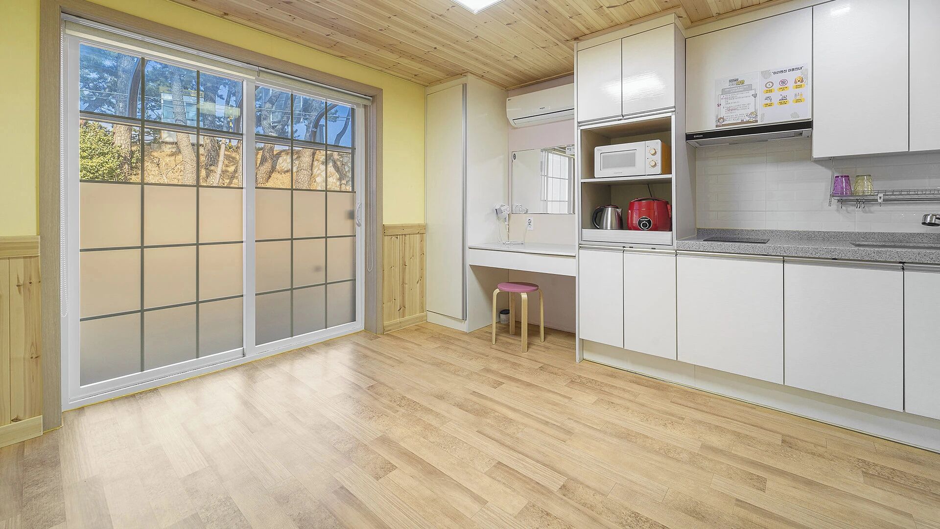 A kitchen with a sliding glass door, white cabinets, a microwave, and a red slow cooker.