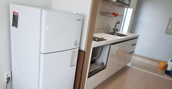Eine kleine Küche mit einem weißen Kühlschrank, einer Spüle und einem Backofen.