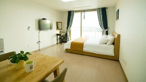 Habitación de hotel con cama, escritorio, televisión y ventana con cortinas.