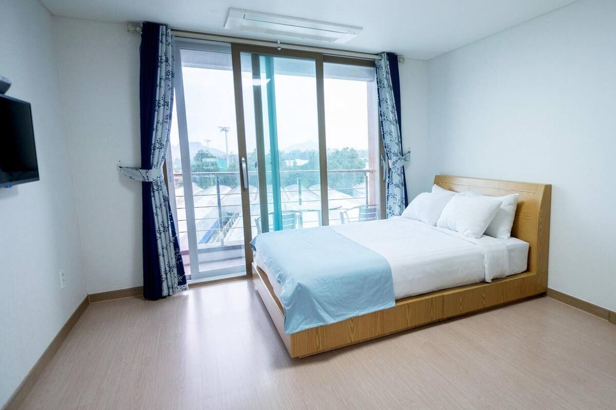 Een slaapkamer met een bed, een televisie en uitzicht.