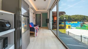 A balcony with a view of a water park, a seating area with a flag, and a refrigerator. - Goseong Bluewhale Glamping (Goseong)