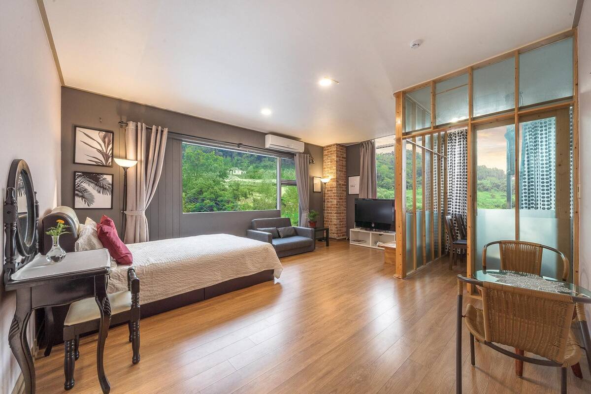 Een moderne hotelkamer met een groot bed, een televisie, een bureau en een eethoek.