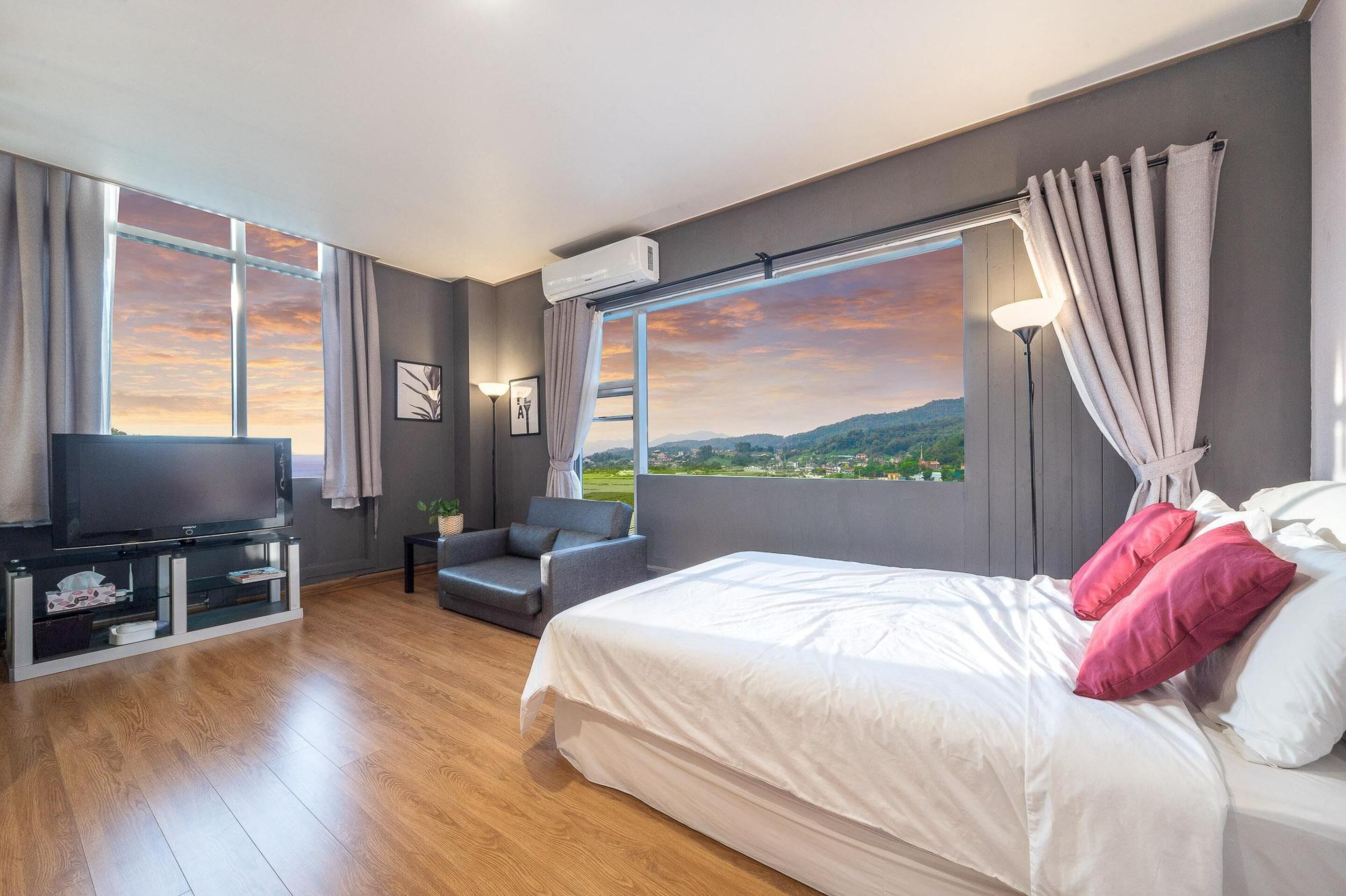 Habitación de hotel moderna con una cama grande, televisión y vistas al campo.