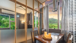 A dining area with a table set for two, a hanging light fixture, and a view of greenery outside. - Ganghwa Chocolate Pension (Incheon)