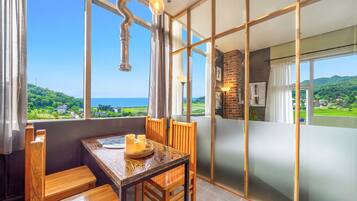 A dining area with a view of the sea, wooden furniture, and a modern interior design.
