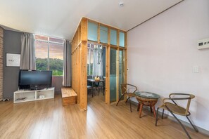 Un salon moderne avec un téléviseur, des meubles en bois et une vue sur la verdure.