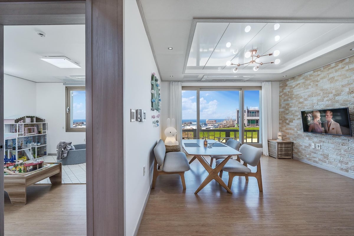 Una sala de estar moderna con comedor, ventanas amplias y televisor.