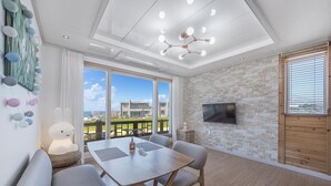 Un salon moderne comprenant un coin repas, de grandes fenêtres, un téléviseur à écran plat et un balcon offrant une vue sur la ville.