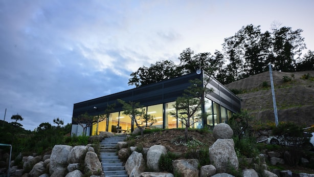 A modern building with a glass facade, a staircase leading up to it, and a rocky landscape surrounding it. - Gwangneung Haeoreum Camping&glamping (Pocheon)