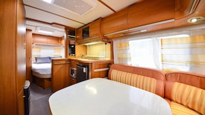 A compact RV interior with a kitchenette, a dining area, and a sleeping berth. - Gwangneung Haeoreum Camping&glamping (Pocheon)