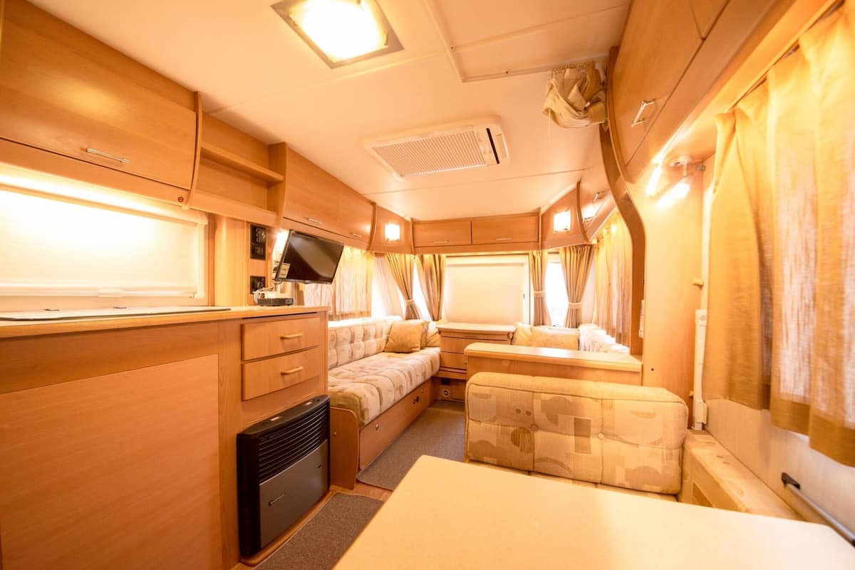 A compact RV interior with a kitchenette, seating area, and a small table.