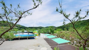 A campsite with tents and a pool area, surrounded by hills and greenery. - Gwangneung Haeoreum Camping&glamping (Pocheon)