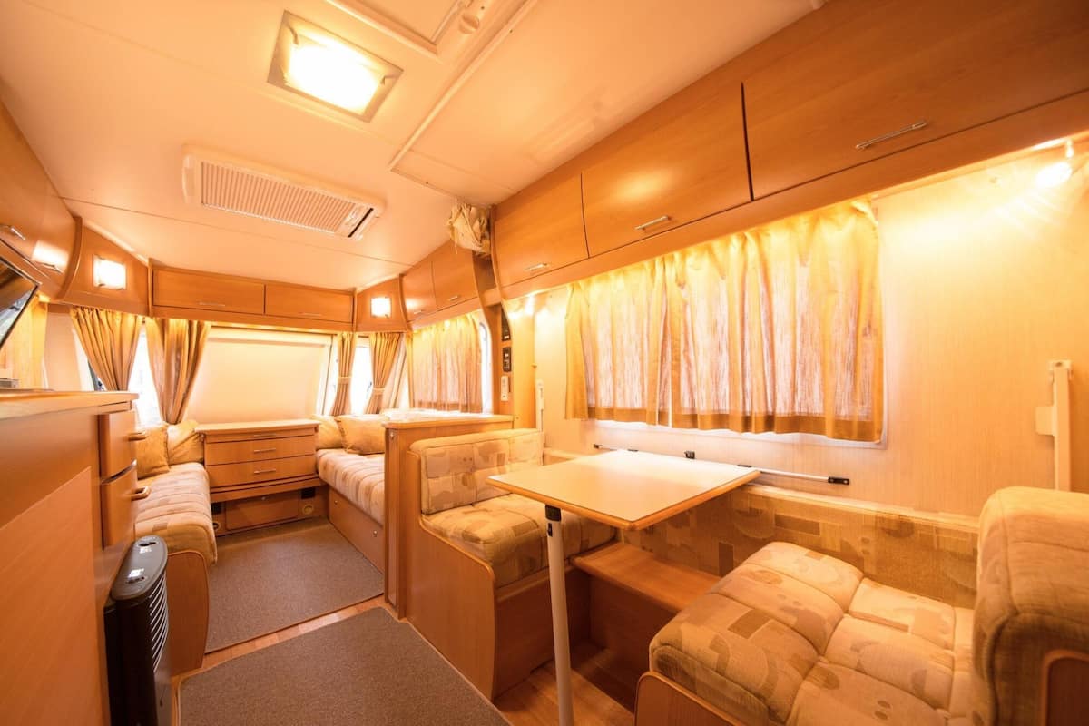 A cozy RV interior with a dining area, a bed, and a kitchenette.