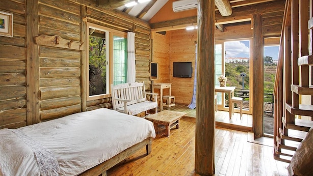 A log cabin room with a bed, a desk, a chair, and a TV. - Jeju Beautiful Resort (Seogwipo)