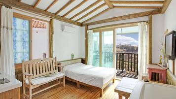 A wooden-framed room with a bed, a bench, and a small table.