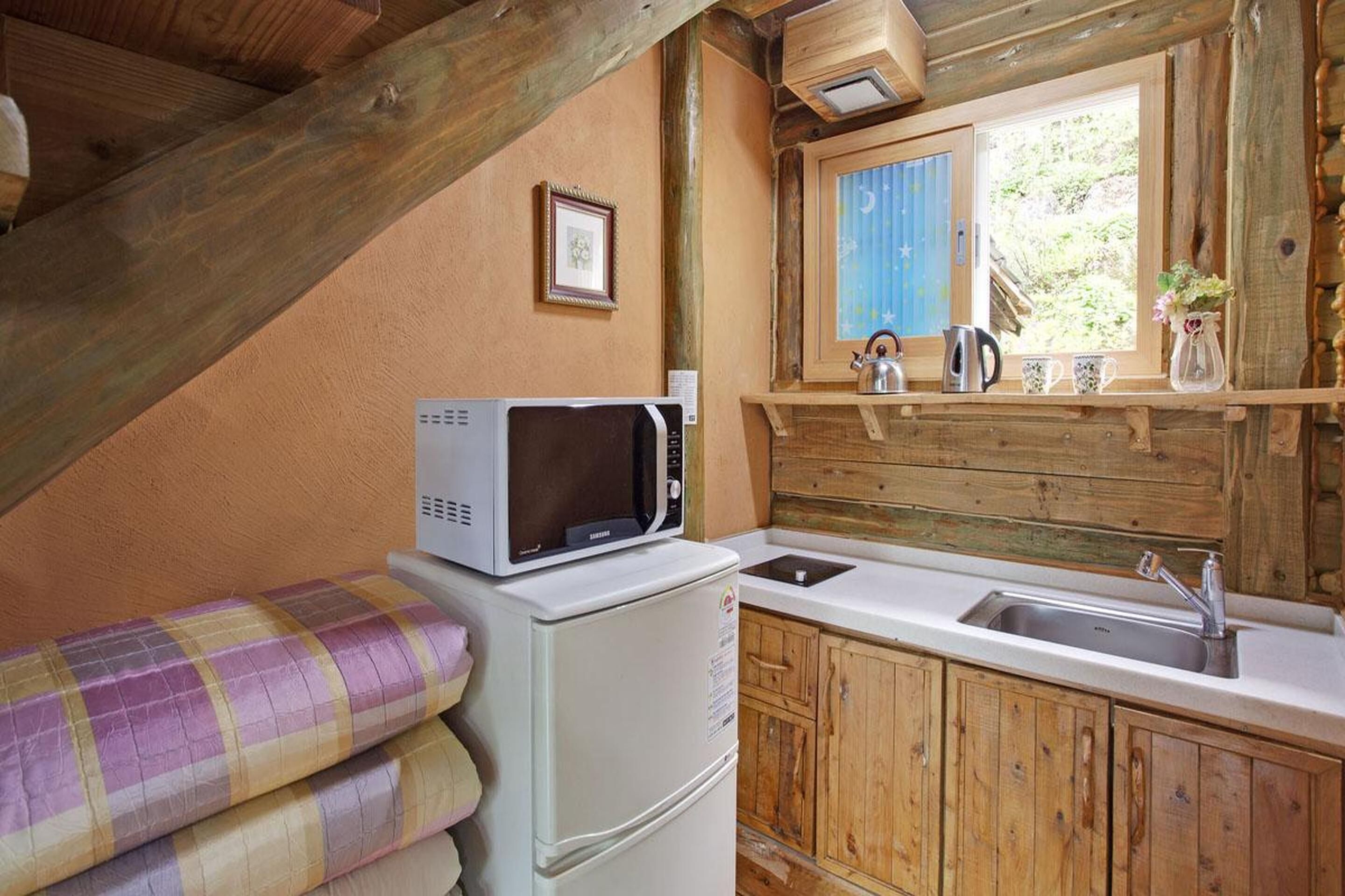 A compact kitchen with a microwave, sink, and wooden cabinets.