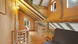 A wooden interior with a sloped ceiling, wooden railings, and a sofa. - Jeju Beautiful Resort (Seogwipo)