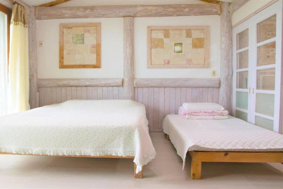 Une chambre avec deux lits, des poutres en bois et une fenêtre avec des rideaux.