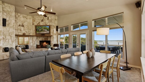 A spacious living room with a stone wall, a large gray sectional sofa, a wooden dining table with chairs, and a fireplace. - Paradise by the lake - Lonestar Lakehouse (Temple)