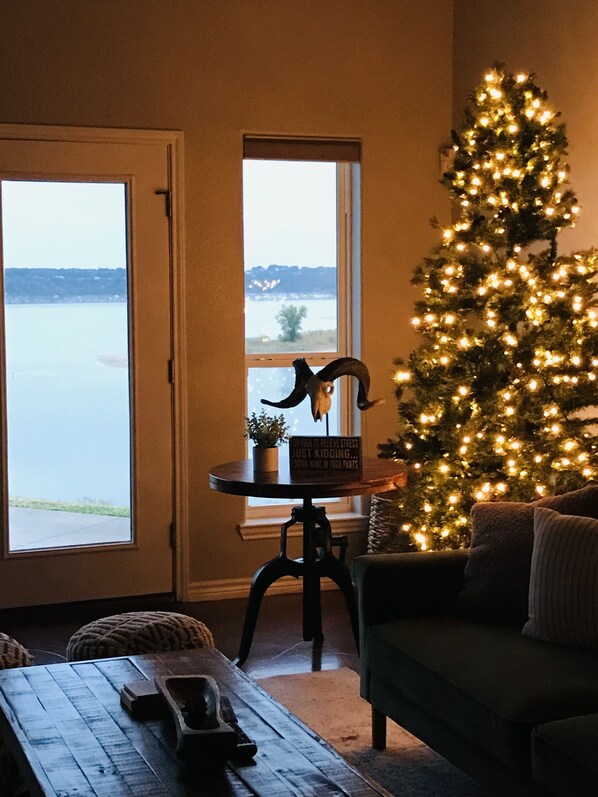 En hyggelig stue med udsigt til en sø, et juletræ og et bord med et skilt.
