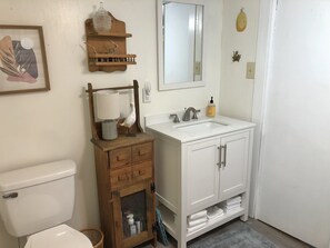 A bathroom with a toilet, a sink with a mirror, wooden shelves, and a cabinet with drawers. - Jocasee Landing Lake Cottage - 1 mi from boat ramp! (Salem)