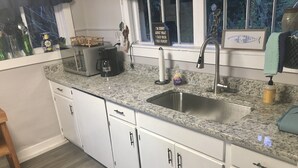 A kitchen with white cabinets, a granite countertop, a stainless steel sink, and a coffee maker. - Jocasee Landing Lake Cottage - 1 mi from boat ramp! (Salem)