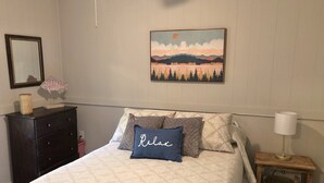 A bedroom with a bed, a dresser, a lamp, and a painting on the wall. - Jocasee Landing Lake Cottage - 1 mi from boat ramp! (Salem)