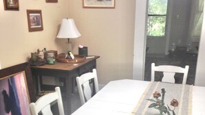 A dining area with a table set for four, a lamp, and framed pictures on the wall. - Jocasee Landing Lake Cottage - 1 mi from boat ramp! (Salem)