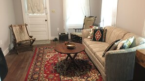 A living room with a beige sofa, a wooden coffee table, a patterned rug, and a hammock chair. - Jocasee Landing Lake Cottage - 1 mi from boat ramp! (Salem)