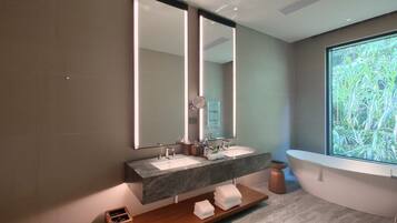 A modern bathroom with two sinks, a large mirror, and a bathtub.