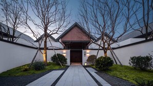 A modern building with a symmetrical facade, a central entrance, and a well-maintained garden with a pathway leading to the entrance. - Ahn Lan Xinchang (Shaoxing)