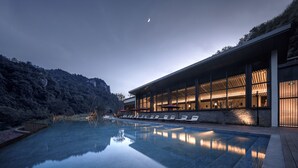 A modern building with a swimming pool, lounge chairs, and a view of a mountain. - Ahn Lan Xinchang (Shaoxing)