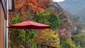 A balcony with a red umbrella, two grey sofas, and a small table. - Ahn Lan Xinchang (Shaoxing)