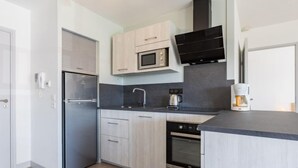 A modern kitchen with a refrigerator, microwave, stove, and coffee maker. - Côté du Lac by Interhome (Soustons)