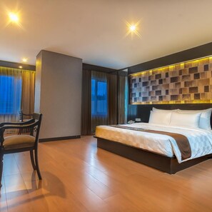 A hotel room with a large bed, a desk, and a view of the outdoors. - Royal Regantris Cendana (Surabaya)